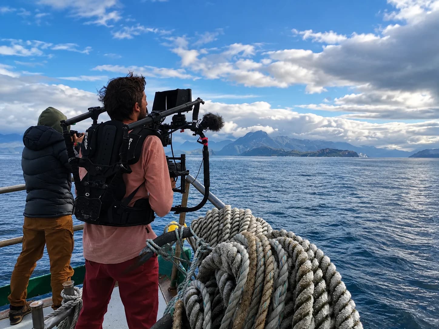 Camarógrafo filmando desde la proa de una embarcación en un canal patagónico
