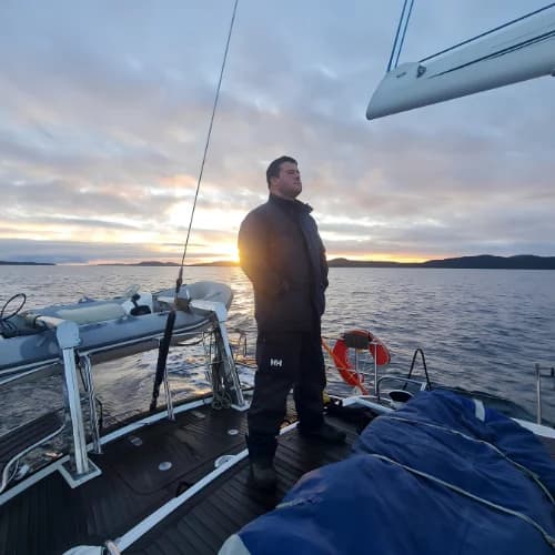 Felipe Jugo a bordo al atardecer, navegando un canal patagónico