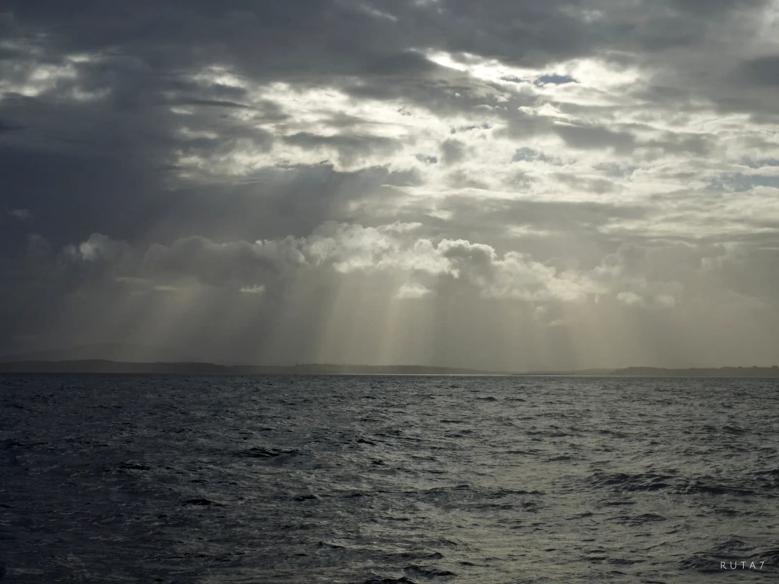 Charter privado Western Patagonia — rayos de sol entre nubes sobre el mar