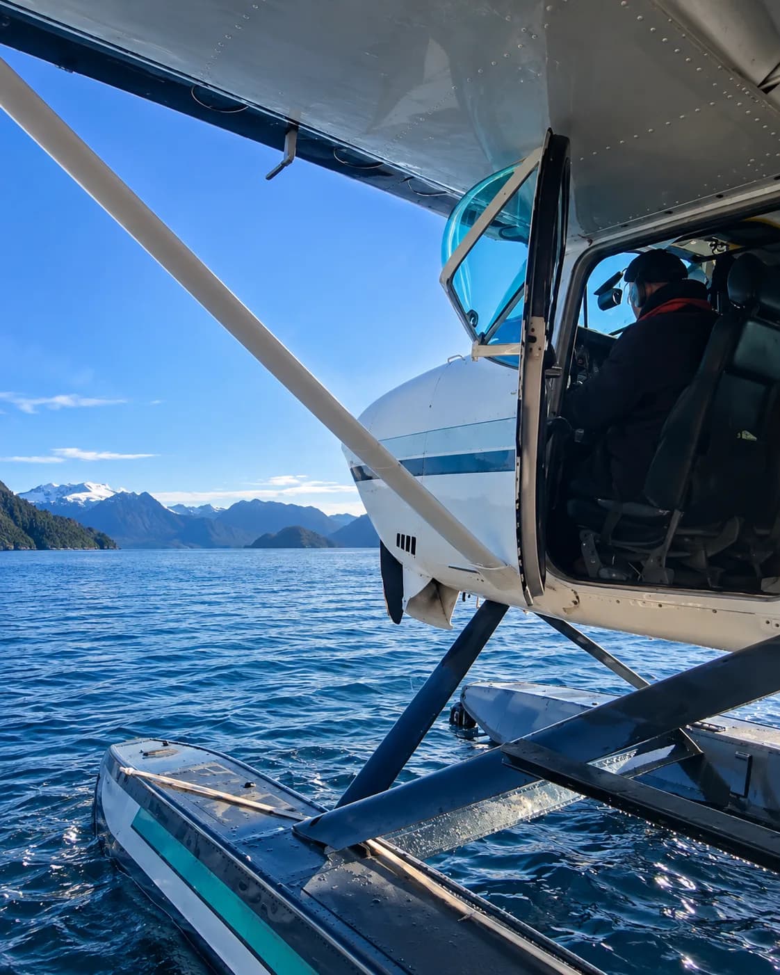 Hidroavión sobre sus flotadores en un fiordo, visto desde el agua