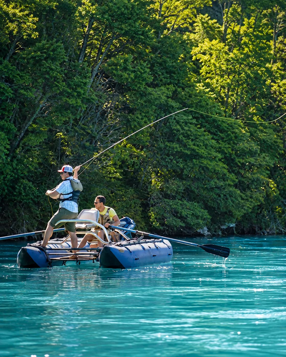 Pesca con mosca desde un bote inflable en un río de aguas turquesa rodeado de bosque