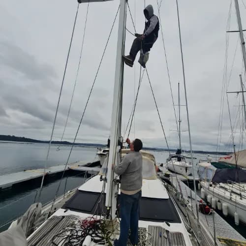 Técnico trabajando en el mástil de un velero en un fondeadero