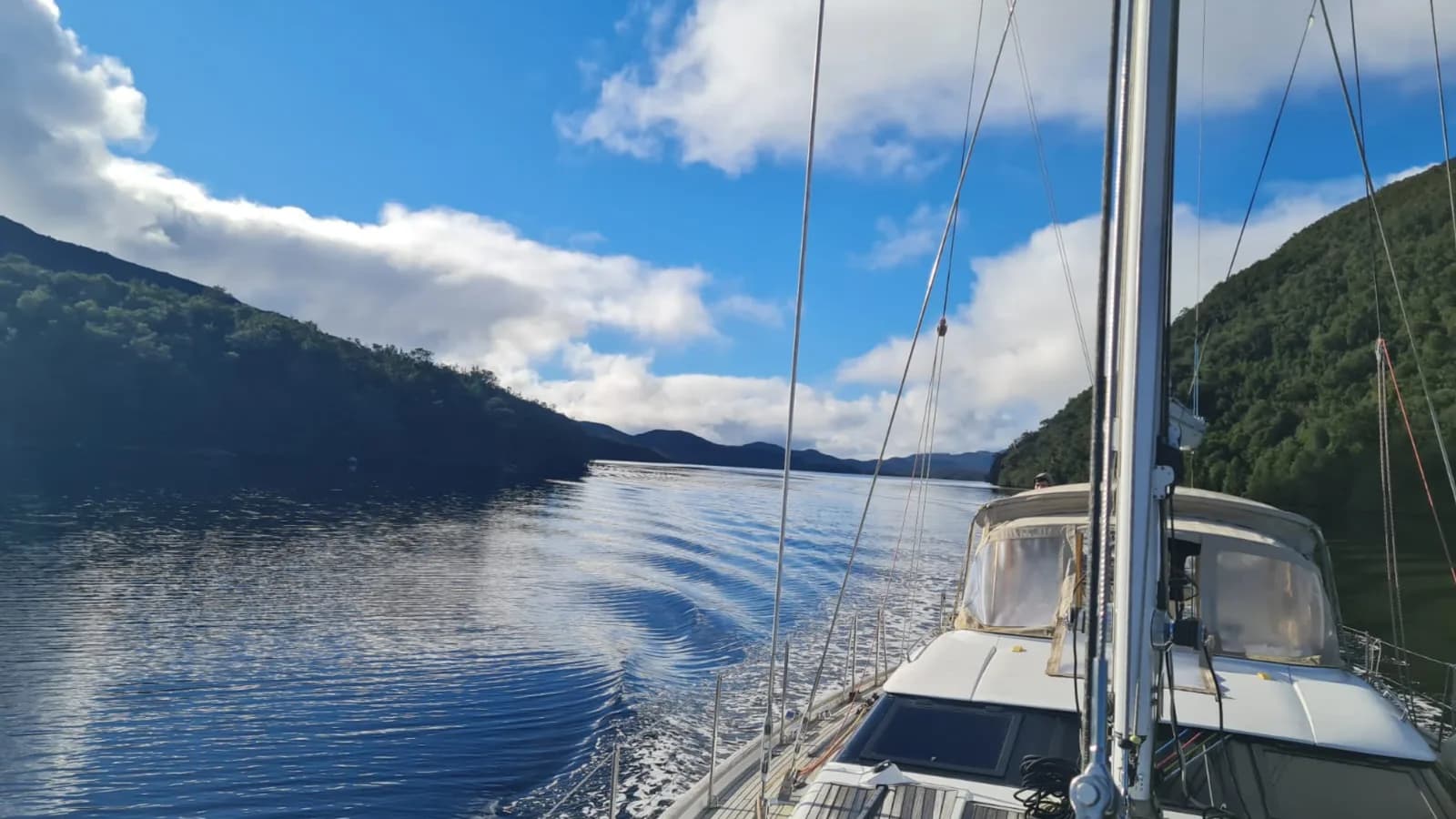 Vista desde la cubierta navegando un canal patagónico, con el timonel a bordo