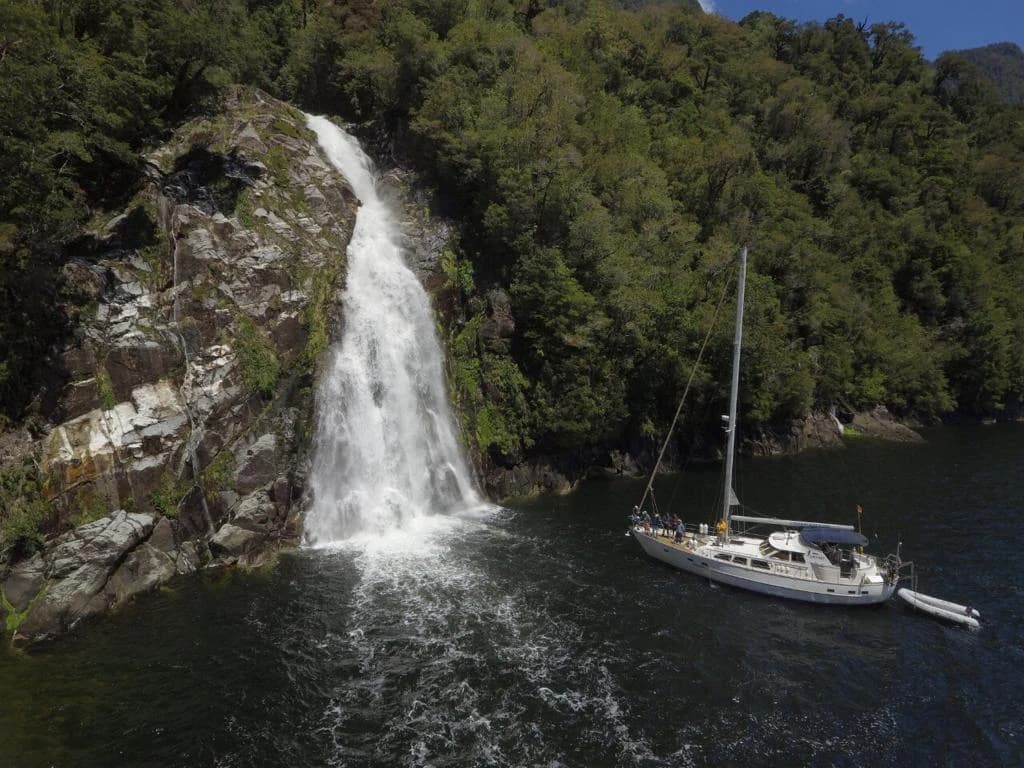 Embarcación junto a una cascada en un canal boscoso