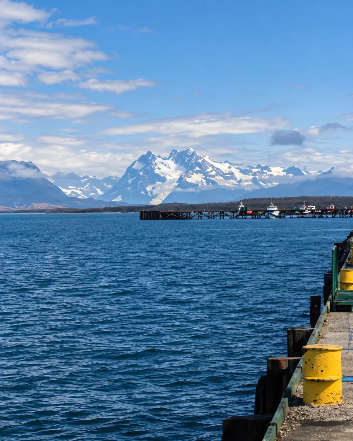 Muelle con embarcaciones amarradas frente a la cordillera nevada, Puerto Natales