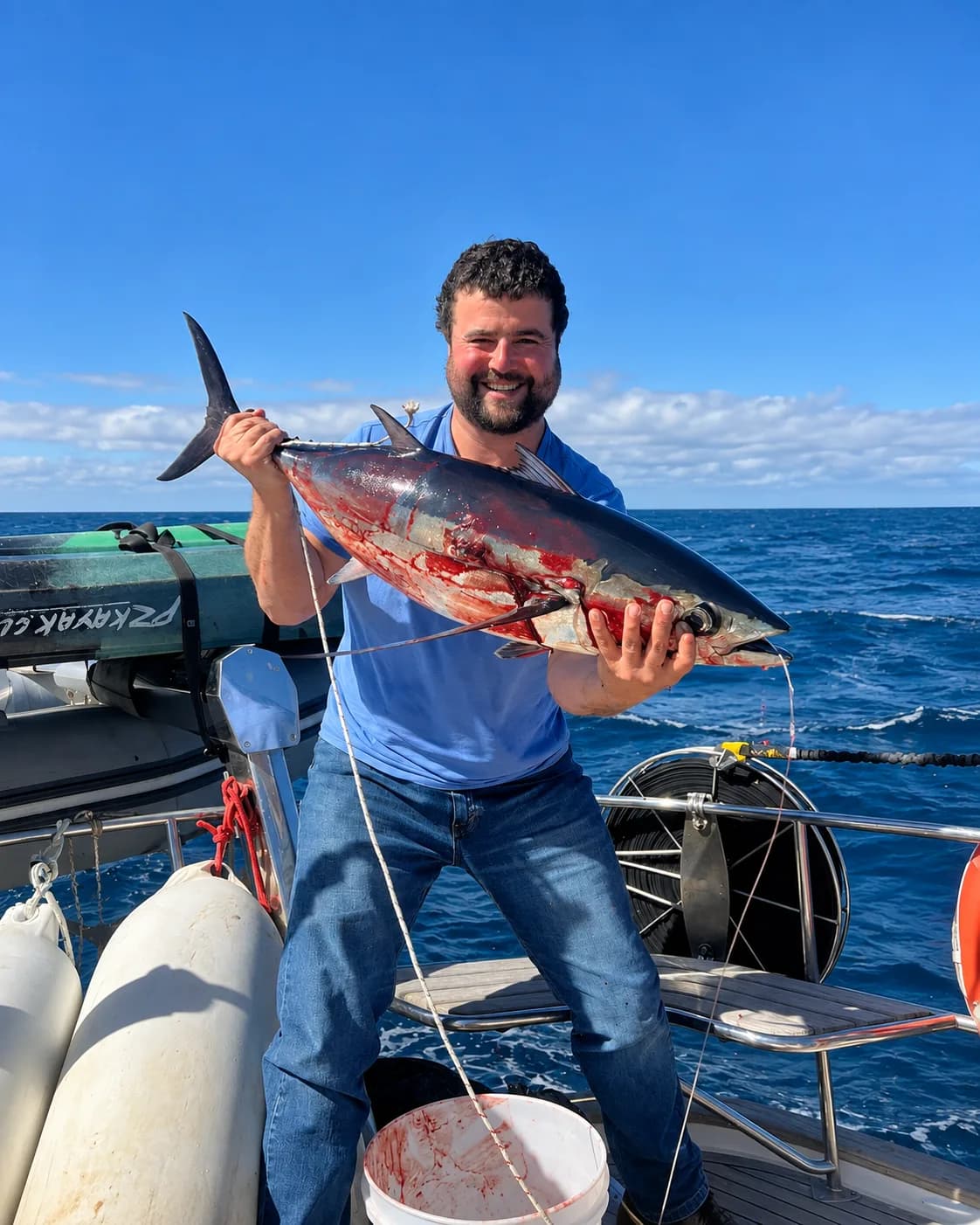 Tripulante sosteniendo un atún recién pescado a bordo, en mar abierto frente a Juan Fernández